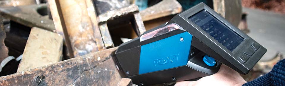 Recyclingmitarbeiter misst Presslinge aus Metall mit handgehaltenem Analysator
